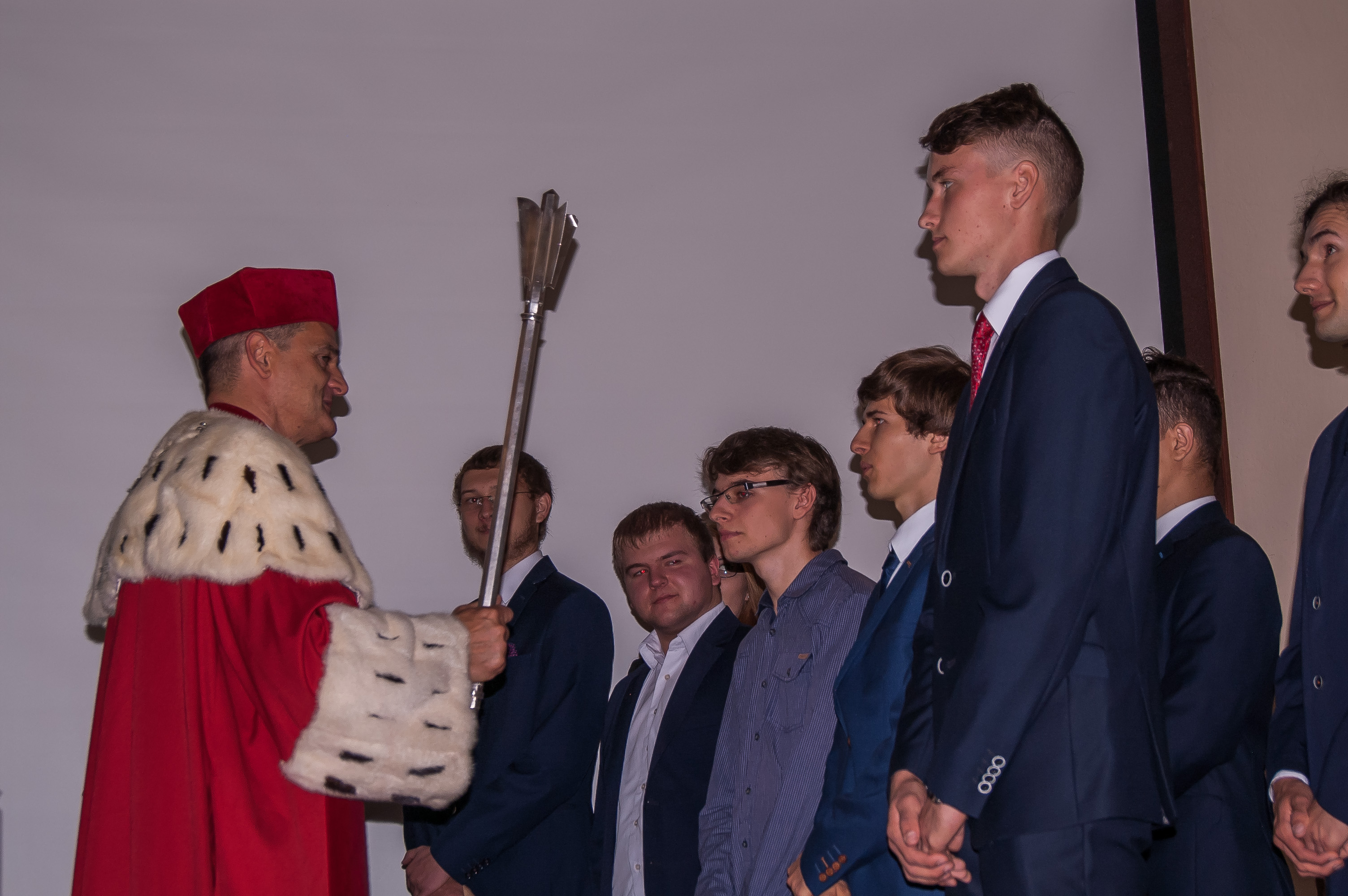 Rektor trzymający insygnia, powołuje studentów pierwszego roku