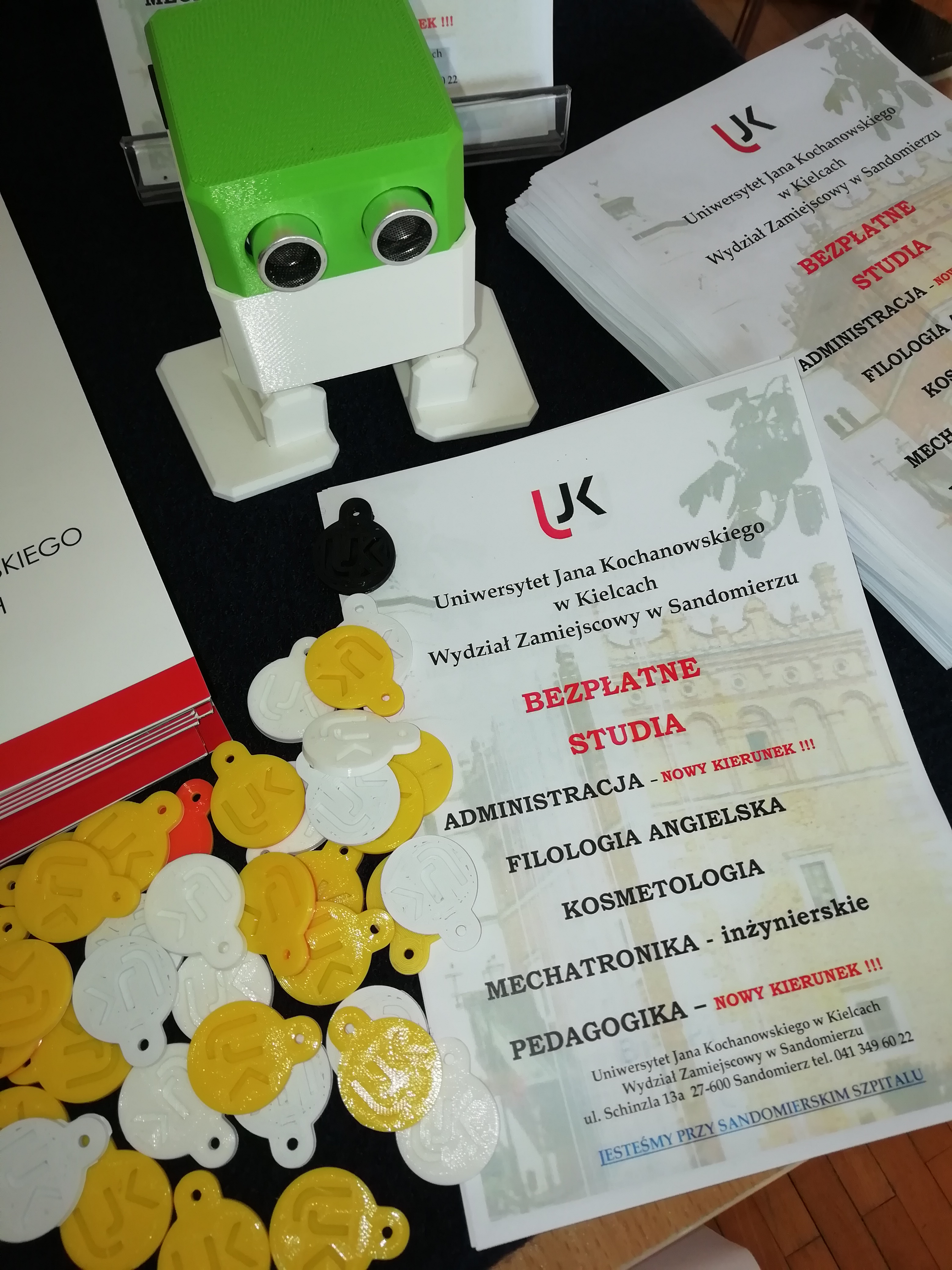 Fotografia ulotki promocyjnej UJK oraz robota wydrukowanego metoda 3d