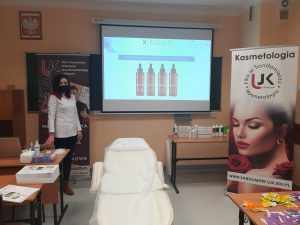 Prowadzaca szkolenie na tle ekranu projekcyjnego i baneru kosmetologia ujk