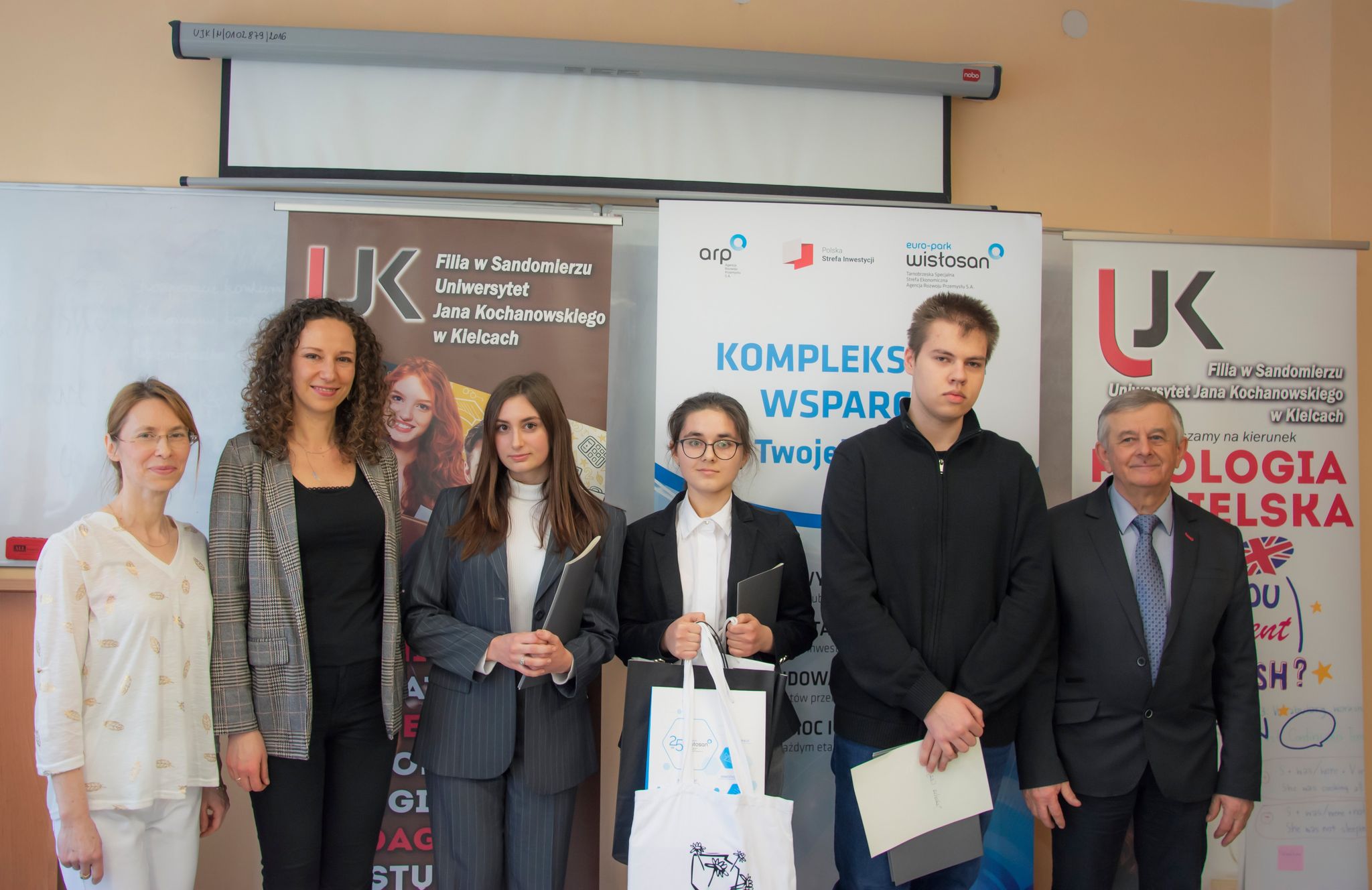 Organizaotrzy konkursu wraz z laureatami na tle banerów UJK oraz agencji rozwoju