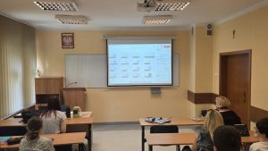 Studenci ogladajacy konferencje na projektorze